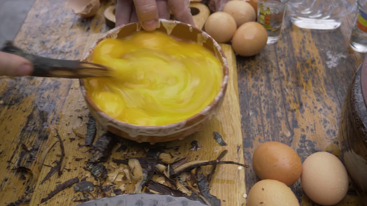 Omelet made in traditional Romanian clay pot. The omelet is made from many eggs and is mixed with a stick from the forest cut with an ax. The omelet is cooked in a cauldron in a primitive style