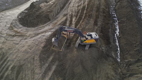 an excavator works in a construction site to remove the earth in an area for a new housing development as seen from an aerial drone vantage point