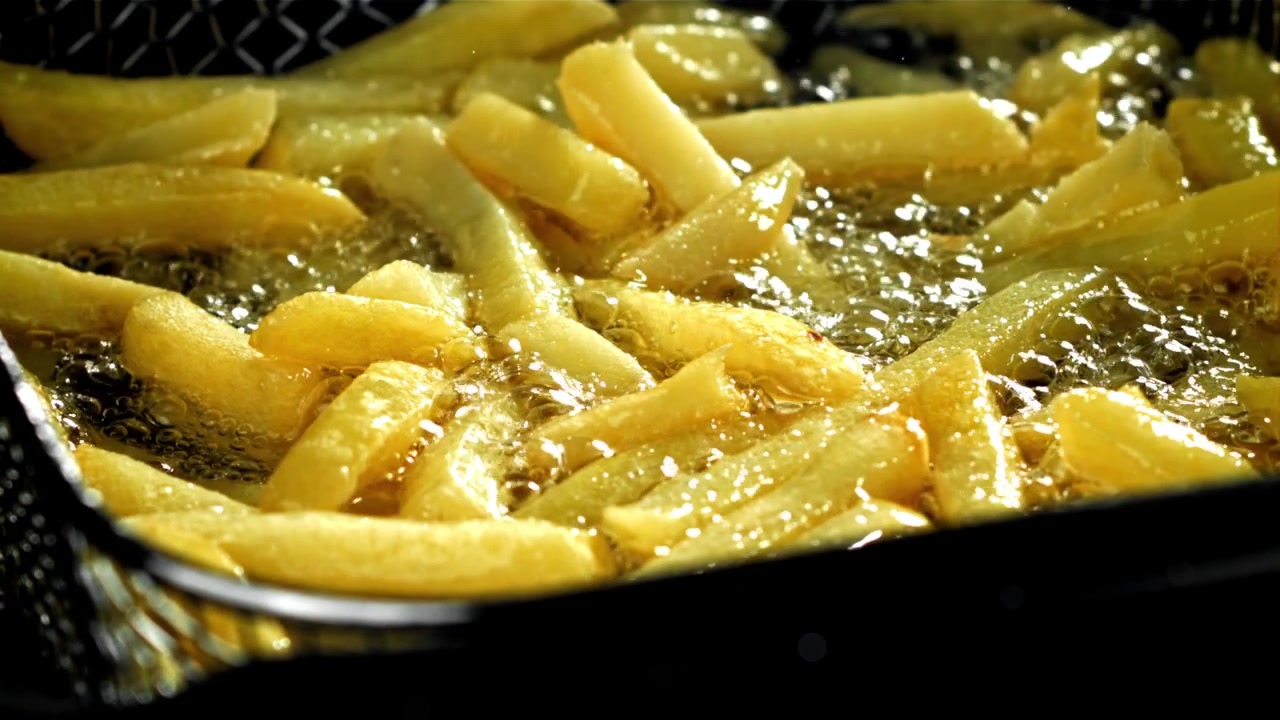 Primo piano di patatine fritte che friggono in olio bollente