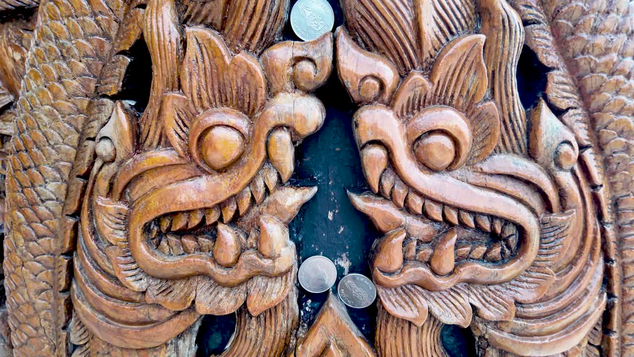 Intricate Thai wood carving of naga dragons on a carved pillar, traditional temple decor and craftsmanship