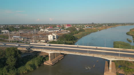 cars speed across the ping river in nakhon sawan thailand drone track left 4k 60fps