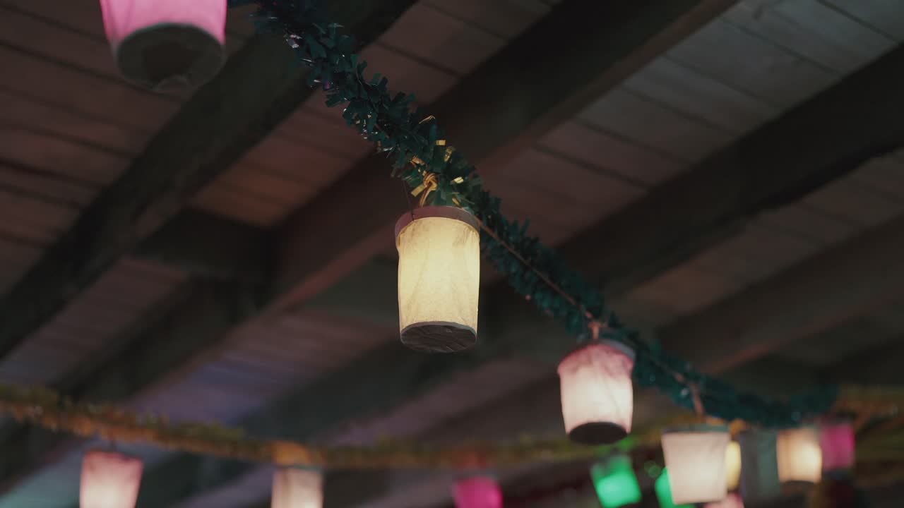 Paper lantern lights hanging from wooden ceiling beams indoors