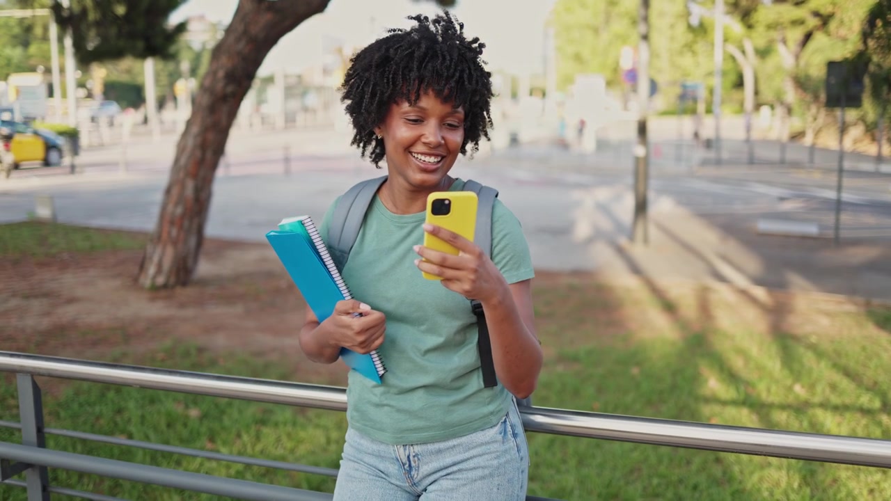 Happy African American Student Using Phone and Looking Around Outdoors