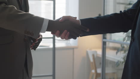 empresarios multiétnicos hablando y estrechándose la mano en la oficina