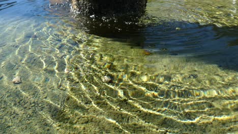 Bonito-Detalle-De-Los-Reflejos-Y-Ondas-De-Agua-De-Una-Fuente-De-Piedra-Con-Salpicaduras-De-Agua