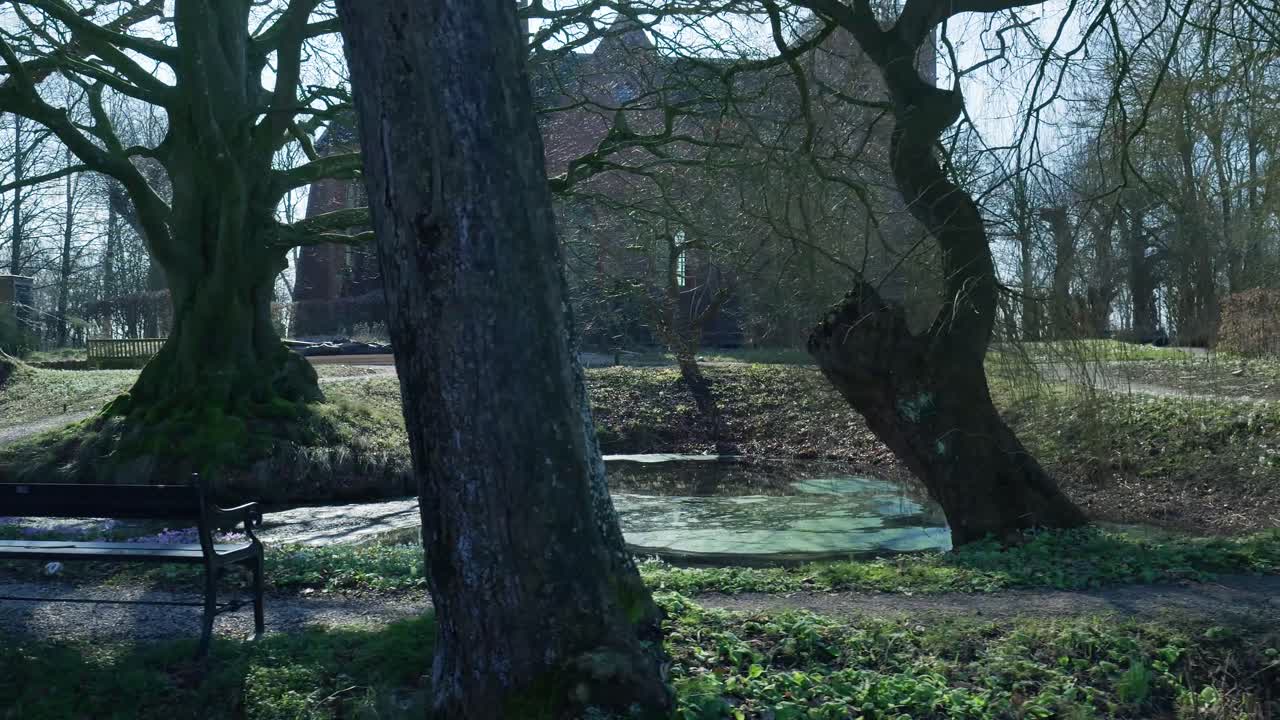Vista panoramica di un castello storico e parco con alberi secolari e stagno