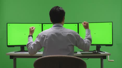 hombre de negocios celebrando el éxito con monitores de pantalla verde