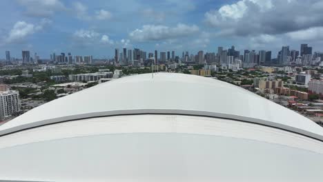 aerial view of a large domed stadium with a city skyline in the background
