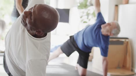 focused group of unaltered diverse senior men practicing pilates with female coach, in slow motion