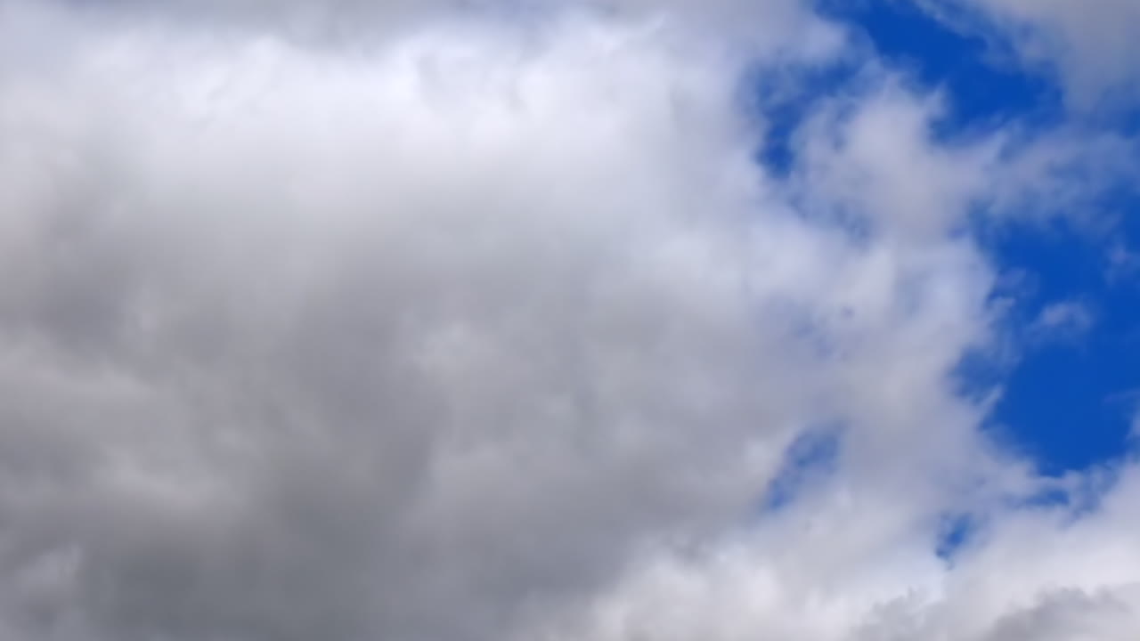 lapso de tiempo de nubes de lluvia oscuras grises y blancas moviéndose a través del cielo con un parche de azul