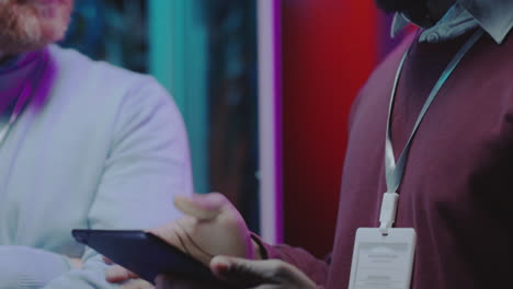 men discussing technology in a neon-lit environment