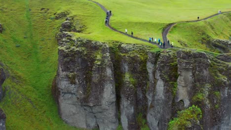 tourists hiking on the trail at the famous fjadrargljufur canyon in iceland