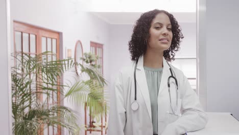 portrait of biracial female doctor wearing lab coat and stethoscope, copy space, slow motion