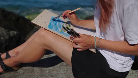 woman painting seascape on the beach