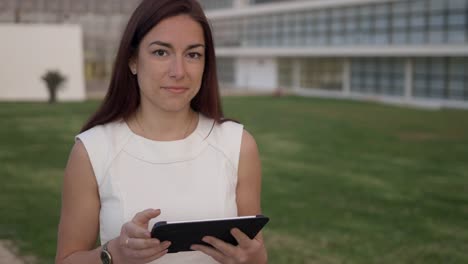 Mujer-Joven-Pelirroja-Sonriente-Con-Tableta-De-Pie-Al-Aire-Libre.