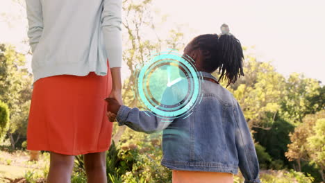 digital clock ticking against african american mother and daughter holding hands walking in the park