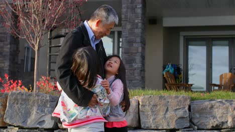 front view of old senior asian grandfather embracing her granddaughters in outside the home 4k