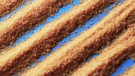 Video-of-close-up-of-pattern-of-yellow-sand-grains-and-copy-space-on-blue-background