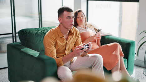 couple relaxing on couch with gaming and smartphone