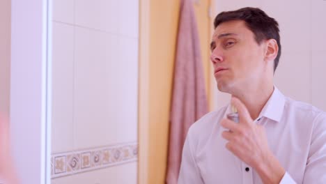 Elegant man applying perfume in bathroom mirror
