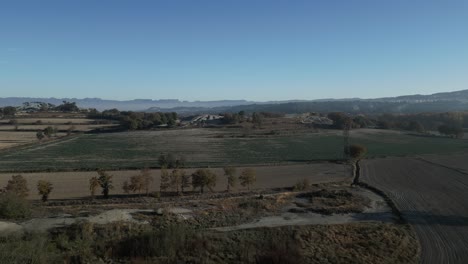 Mediterranean-fields-at-Malla-Barcelona-Spain-wide-skyline-late-winter-Aerial-Drone,-pale-green-trees,-brown-meadows-and-skyline-in-European-Landscape