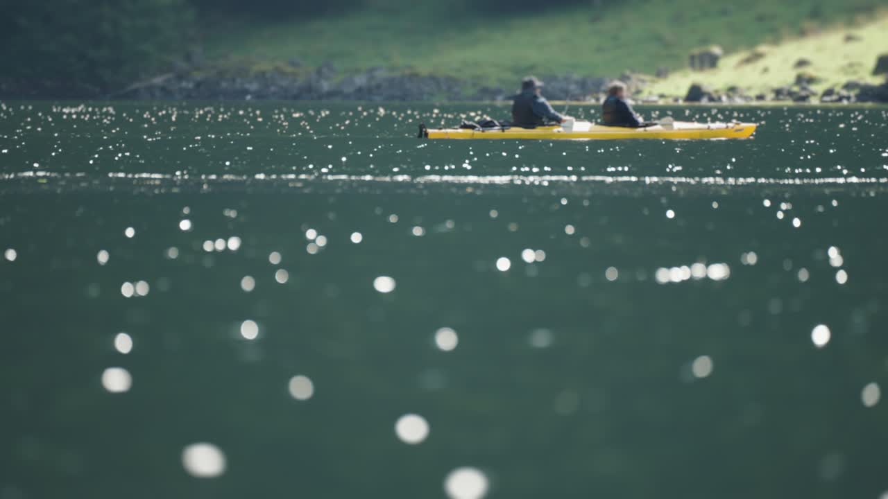 Two people kayaking on a sparkling lake