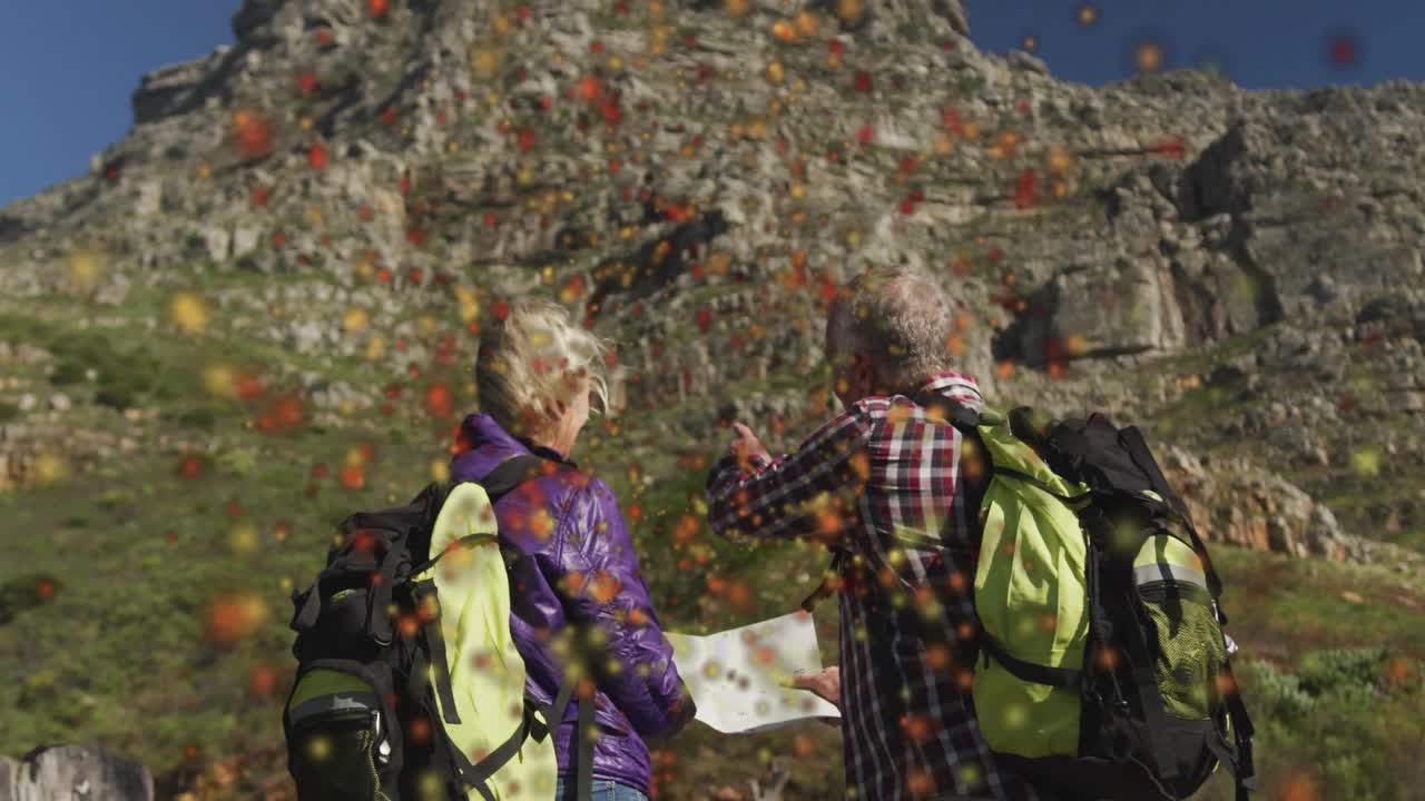 Couple holding map mountain base watching leaves swirling pointing slope confirming hiking route