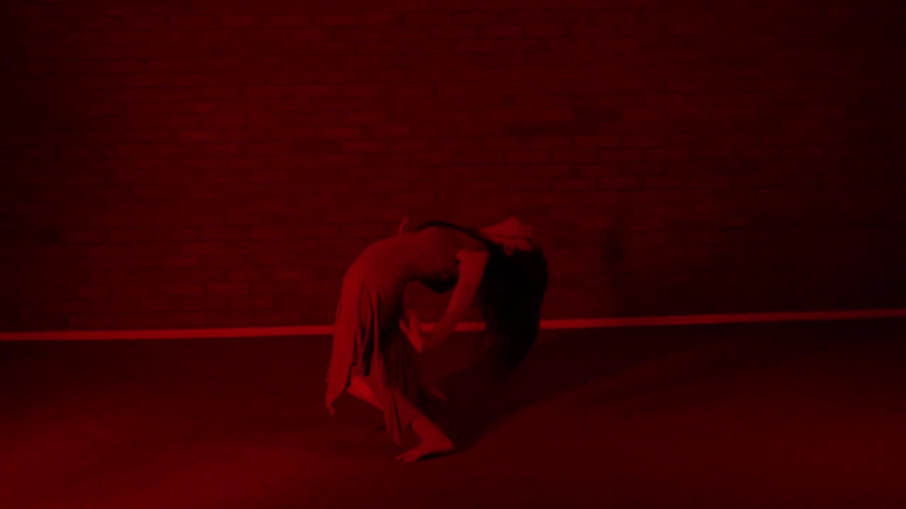 Straordinaria danzatrice che si esercita in una stanza rossa.