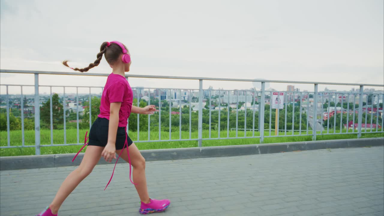 A Young Girl Enjoys Her Playful Adventure While Jumping Rope and Listening to Music in a Scenic Outdoor Setting Under a Beautiful Sky