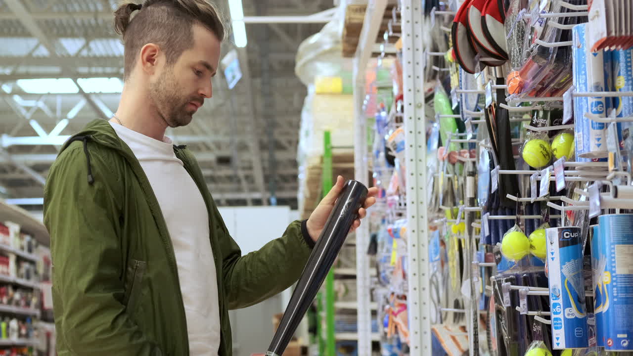 hombre mirando un bate de béisbol en una tienda de deportes
