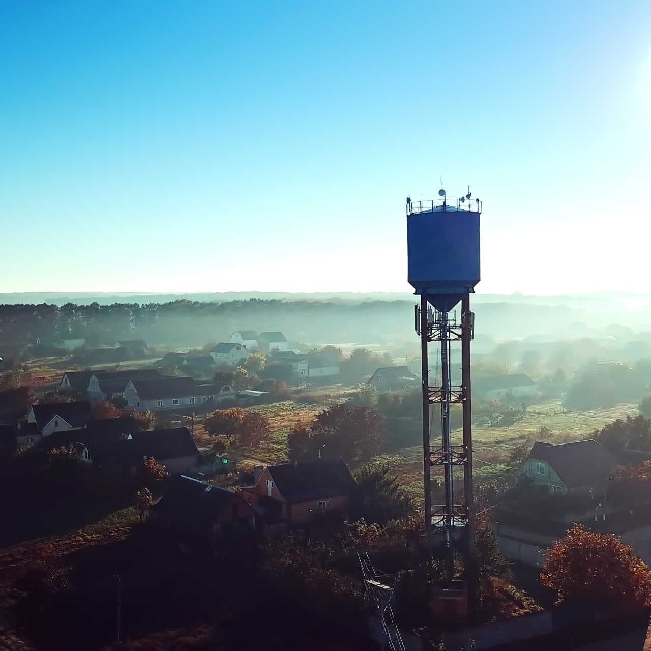 Dron shot aerial over the countryside and the big steel tower at sunrise. High metal construction in the rural place in the morning dawn. Camera moves left.