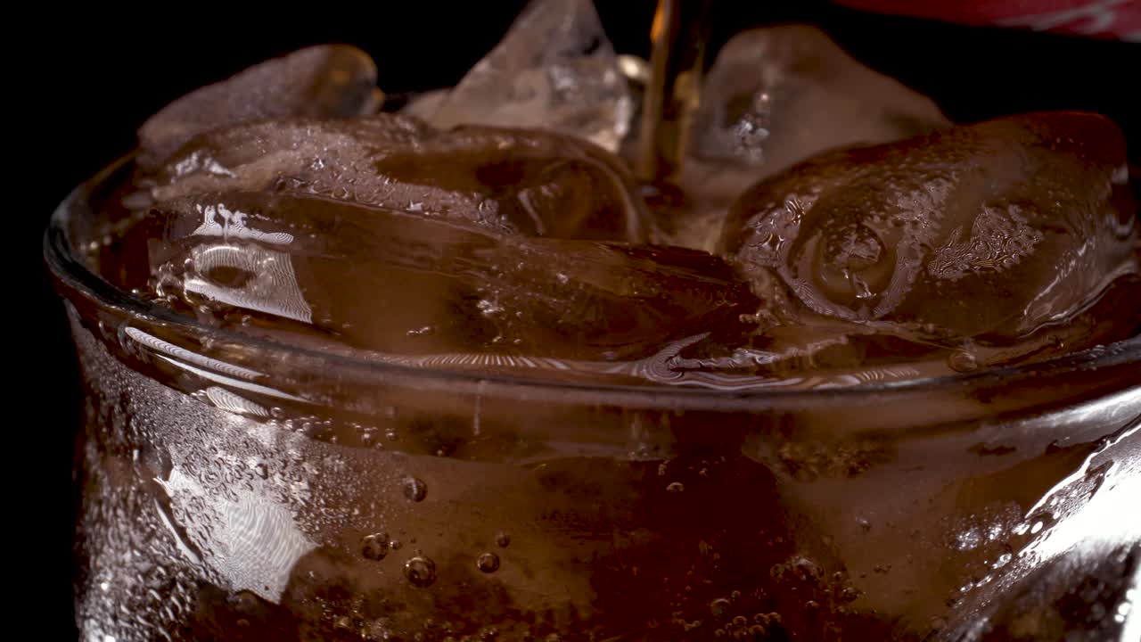 유리에 콜라와 얼음, 콜라가 얼음 덩어리가 있는 매력적인 유리에 쏟아집니다