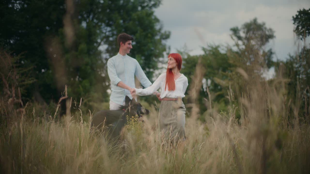 Couple walking with a dog in a field