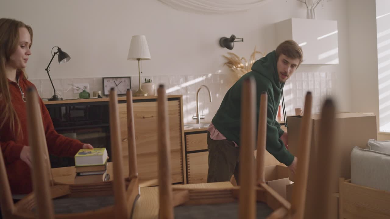 пара переносит мебель и распаковывает коробки