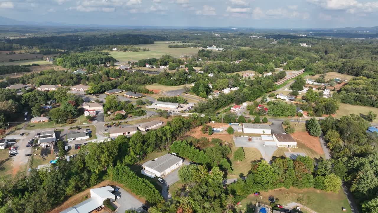 Aerial establishing shot of suburb neighborhood with farm houses and green trees in summer. Houses and companies on rural district of town. Virginia ,USA