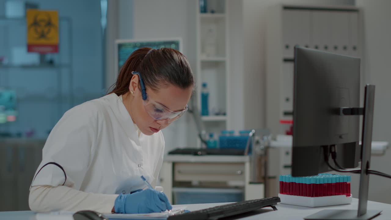 Woman chemist taking notes for science research in laboratory