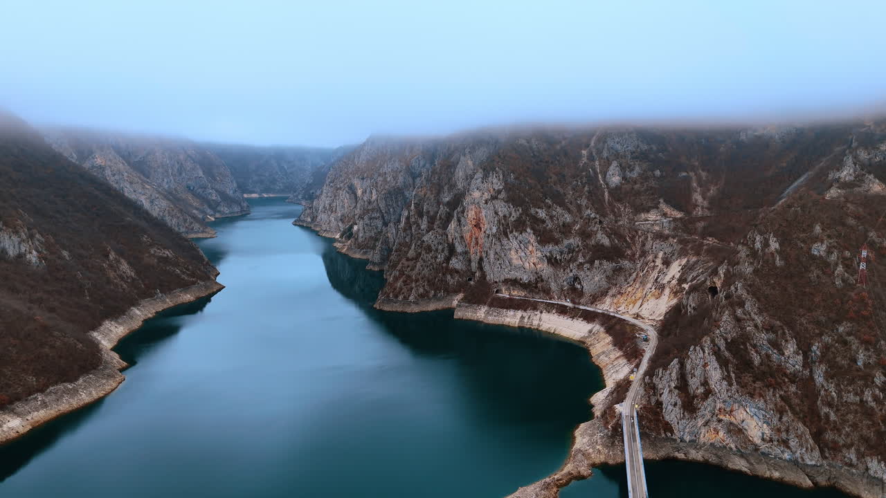 Veduta aerea del canyon del fiume Piva con nebbia in Montenegro. Veduta dall'alto di un fiume turchese che serpeggia tra montagne rocciose coperte di nebbia nel paesaggio montenegrino