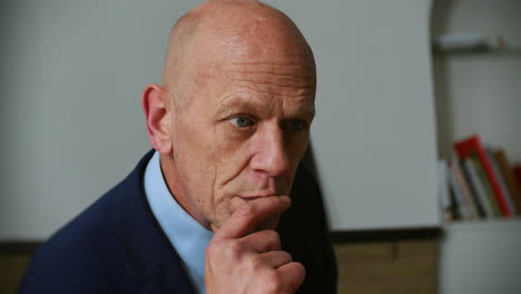 a pensive mature businessman is sitting in at a desk