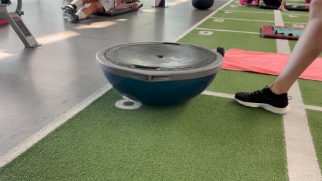 Young-Caucasian-woman-doing-push-ups-from-fitness-ball-while-training-in-gym-indoors