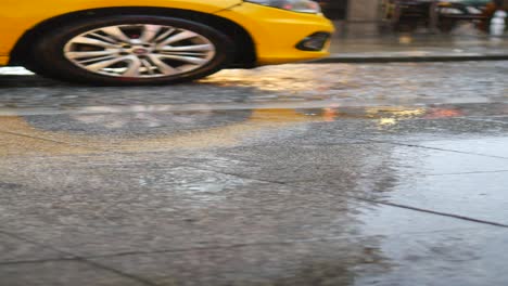 a yellow taxi driving down a wet city street