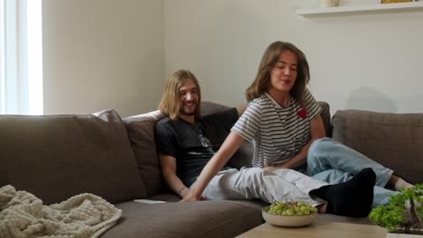 man using a cell phone as a woman sits to eat fruit grapes. static shot