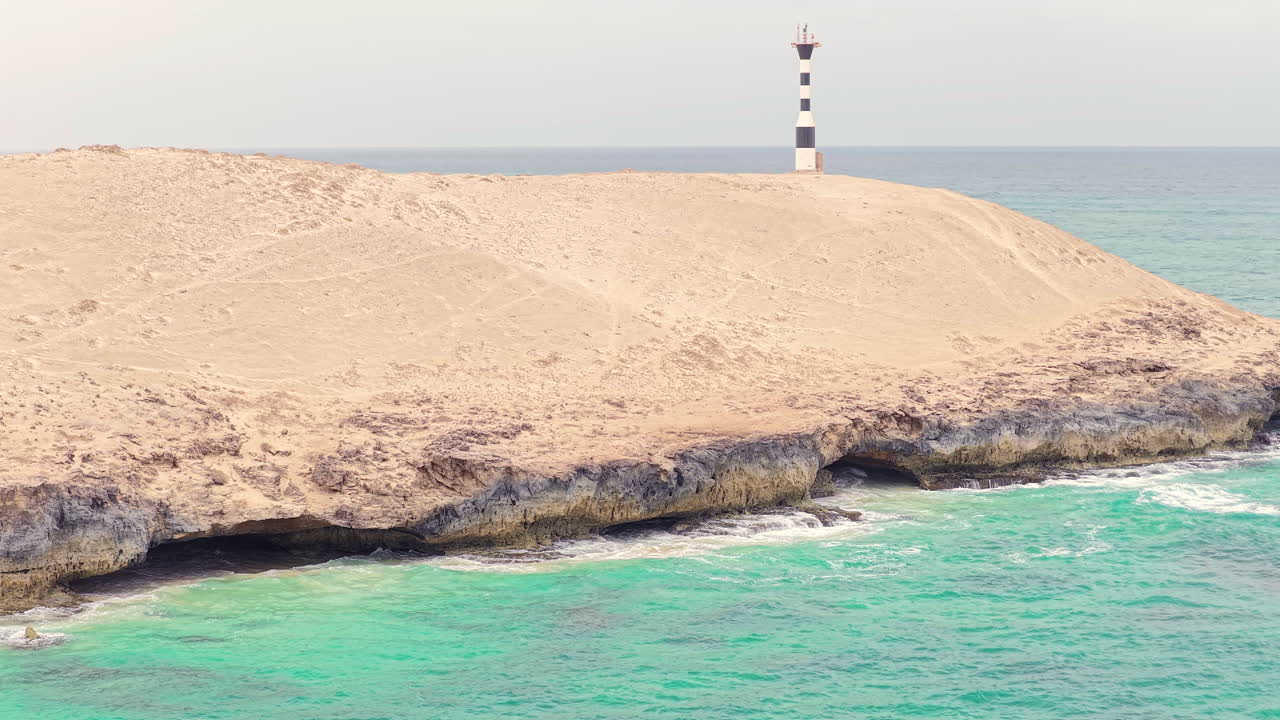 Aerial view of Varandinha shore,beach is divided by rocks that outline its contour creating a wonderful landscape,in the end of the rocks there a lighthouse close-up,Boa Vista,Cape Verde