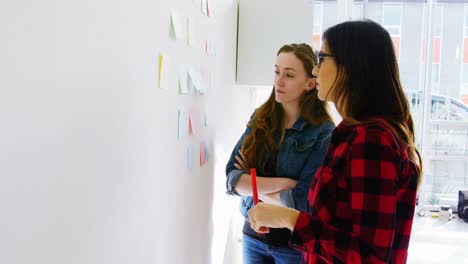 Female-executives-discussing-over-sticky-notes