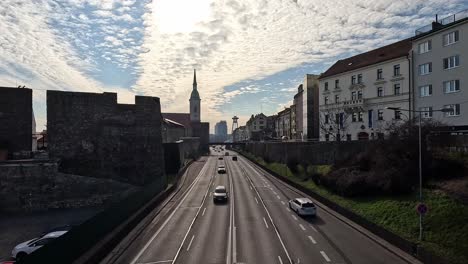 traffic flows along highway beneath st. martin’s cathedral and bratislava castle walls under dramatic cloud-filled sky in bratislava, slovakia