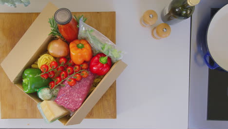 vista desde arriba de una mujer poniendo una caja de ingredientes frescos entregados en el mostrador de la cocina - tomada en cámara lenta