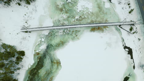 icy river and snowy mountain landscape in norway - aerial shot