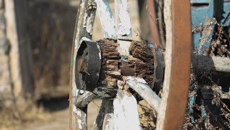 Bright-and-sunny-close-up-of-a-old-patinaed-wood-and-steel-wagon-wheel-parked-outside-a-stone-concrete-farm-building