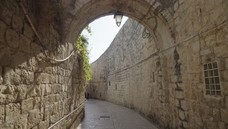 walking through narrow alley with arch passage between high stone and brick walls in jerusalem - pov