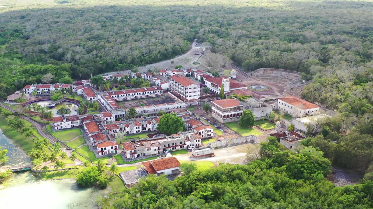 Ripresa aerea con drone dell'hotel fantasma abbandonato accanto alla Laguna dei Sette Colori a Bacalar, Messico. Rovine uniche circondate da acqua turchese, natura tropicale e scenari di viaggio iconici