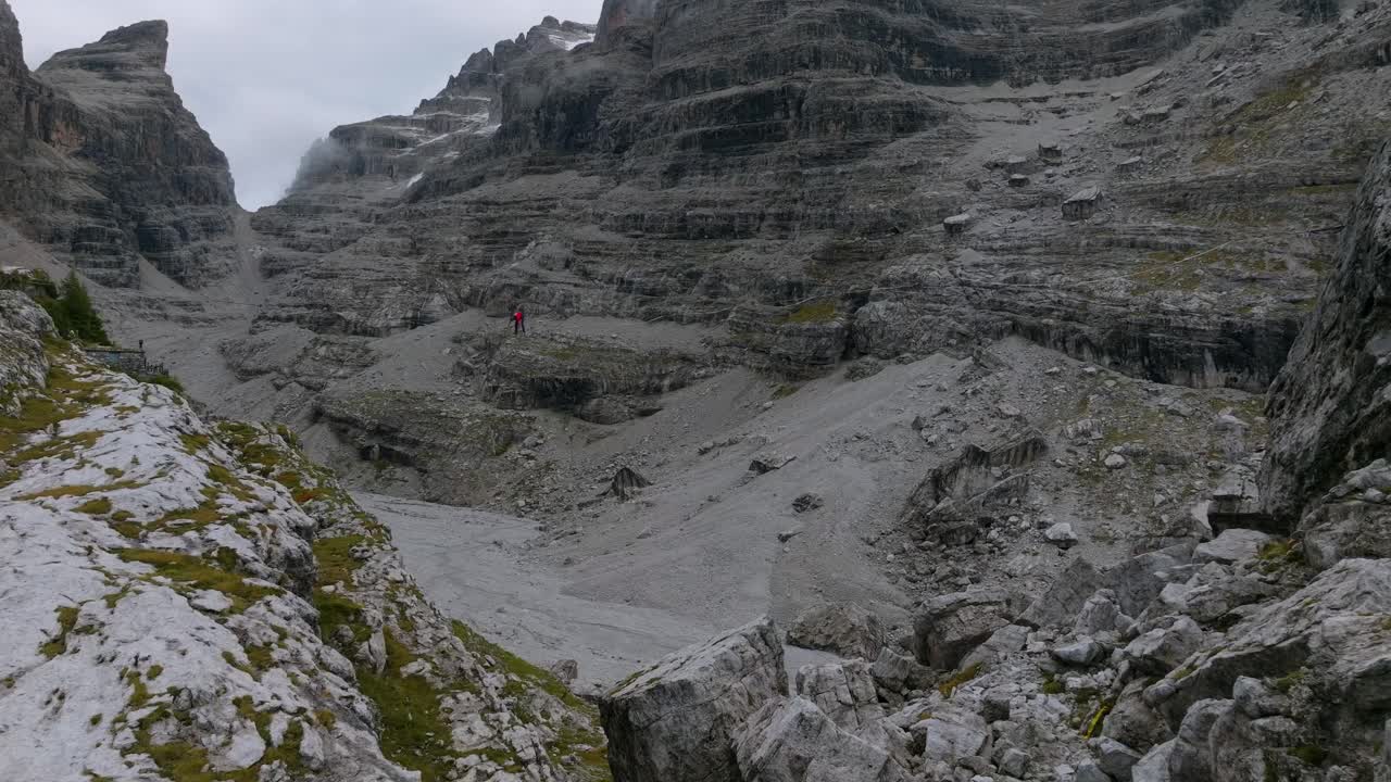 disparo de drone que muestra a una persona saltando en slackline entre montañas rocosas al aire libre